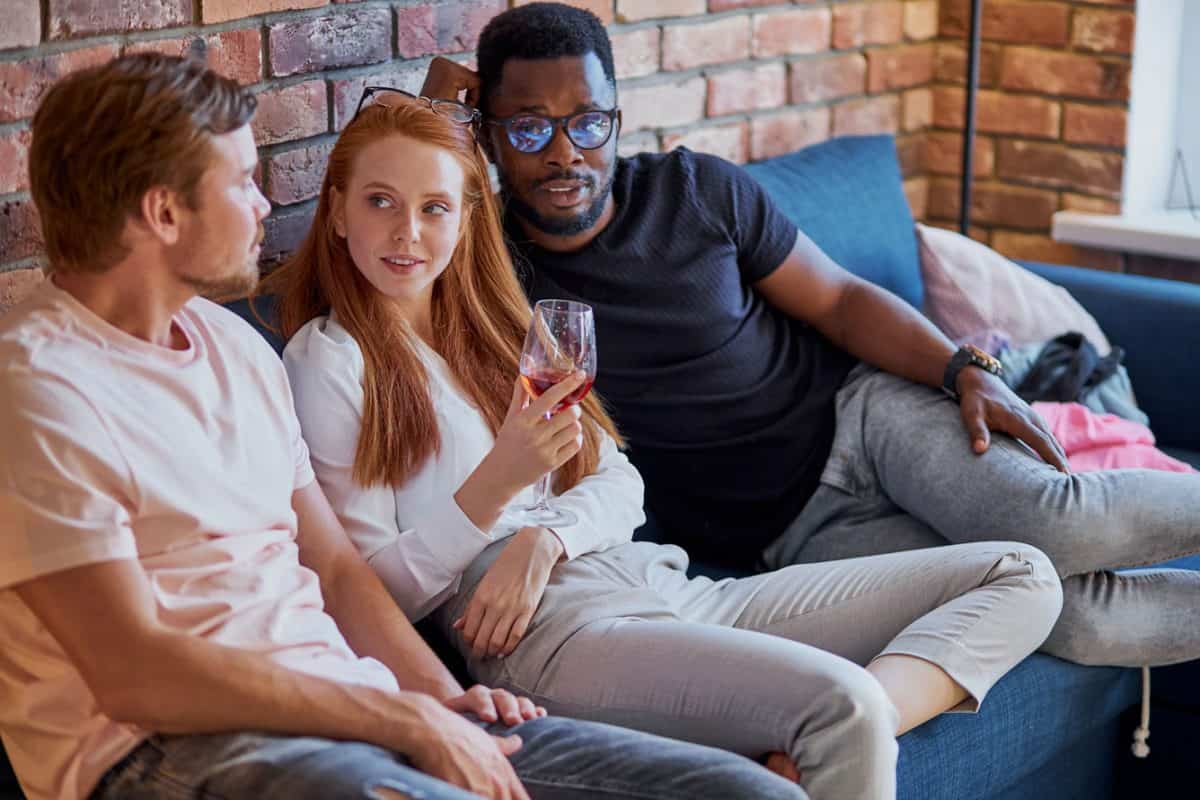 2 men and one woman on sofa
